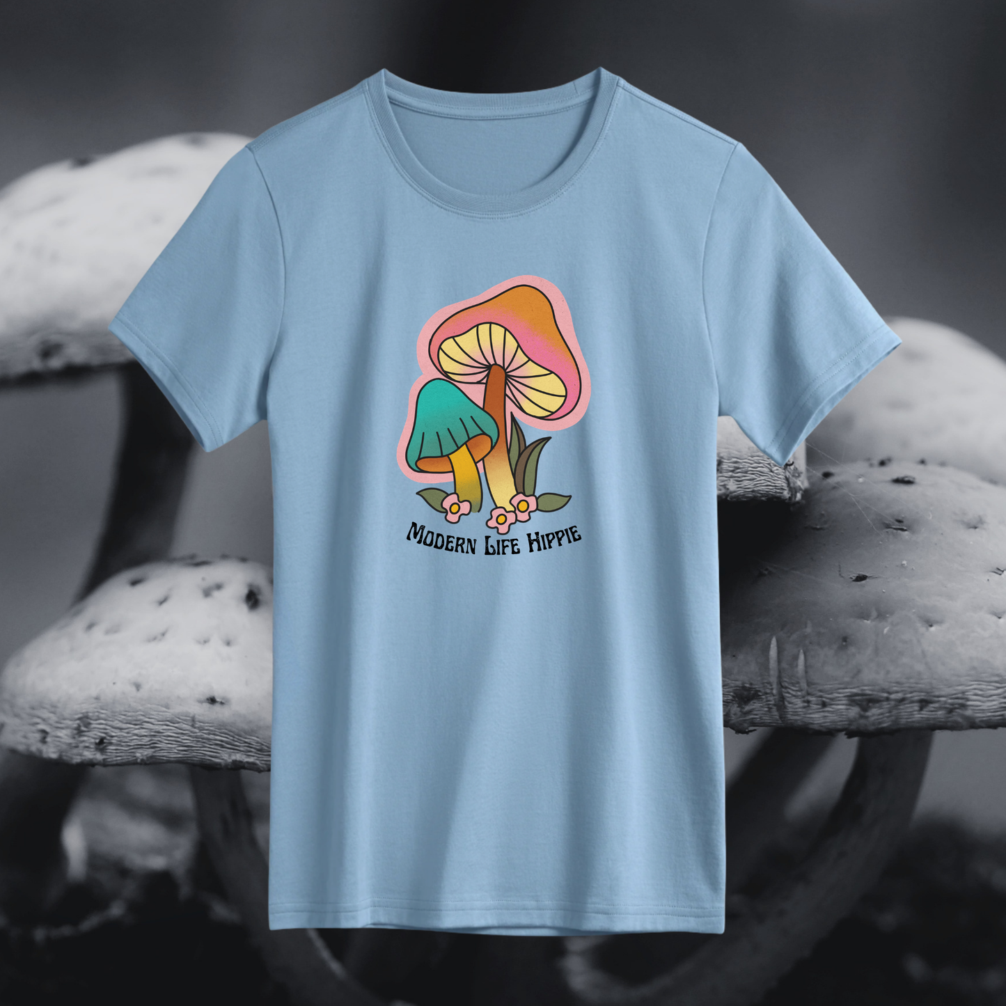 Light blue t-shirt with a colorful mushroom graphic and 'Modern Life Hippie' text on a blurred mushroom background.