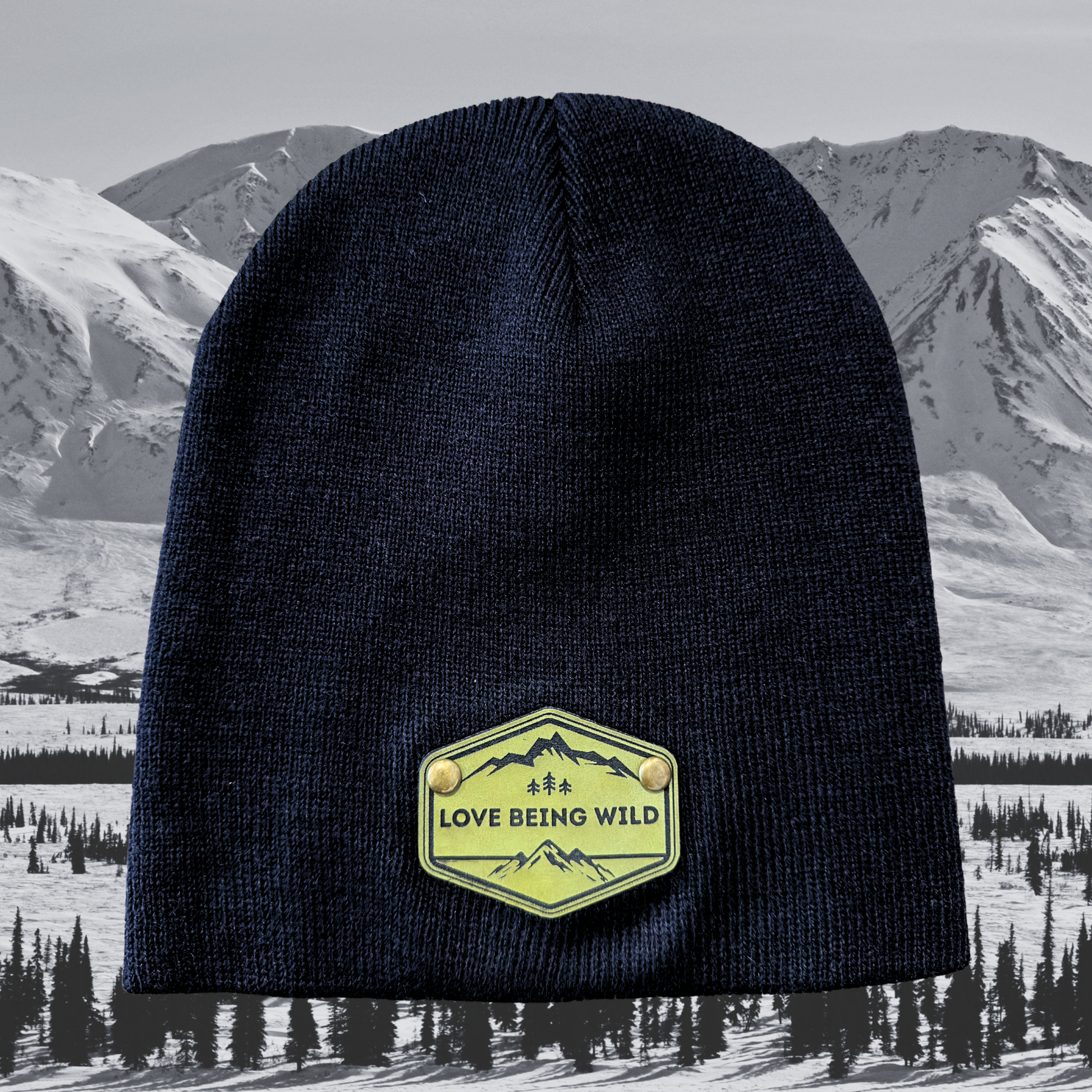 Black beanie with a 'Love Being Wild' patch against a snowy mountain background