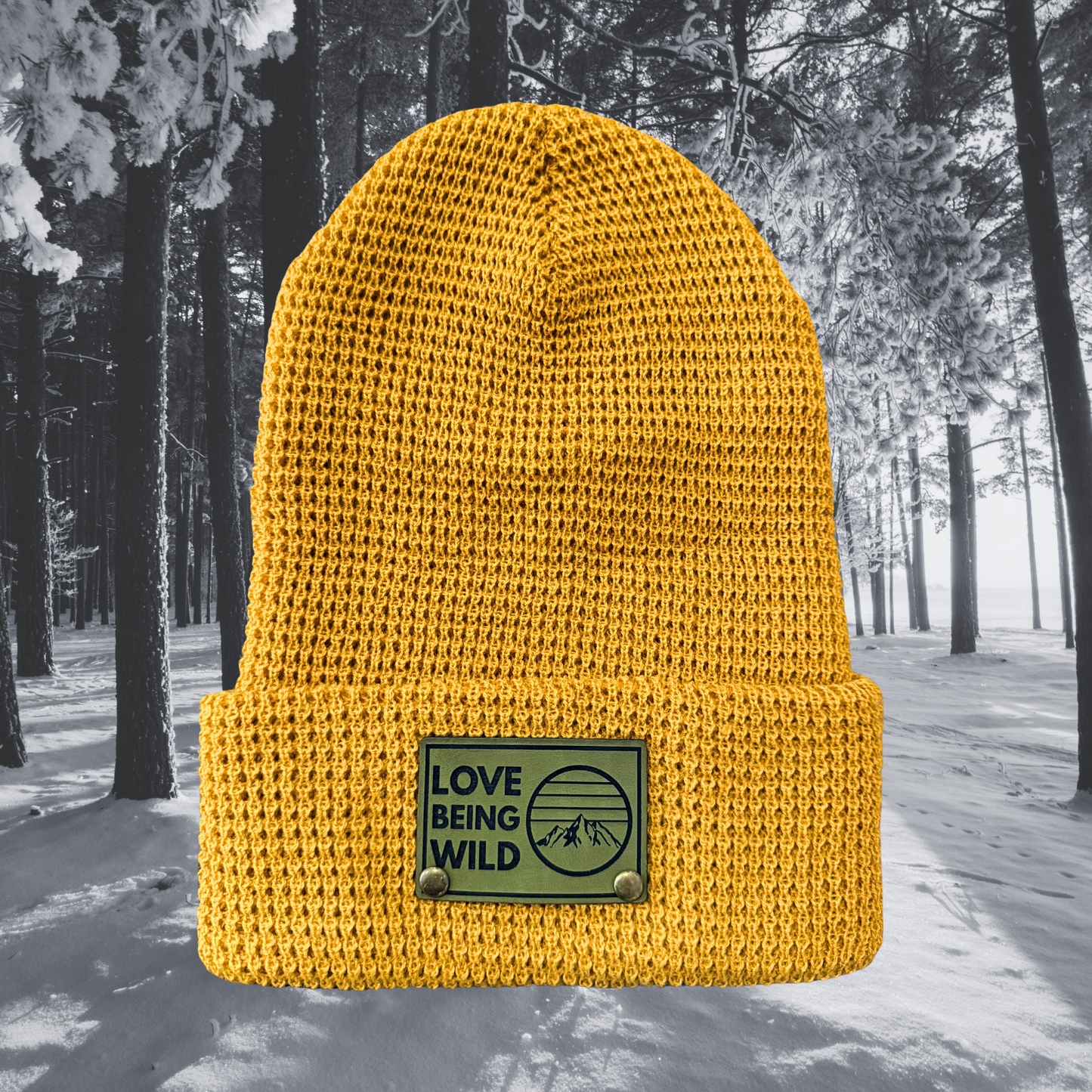 Yellow beanie with a 'Love Being Wild' patch against a snowy forest background