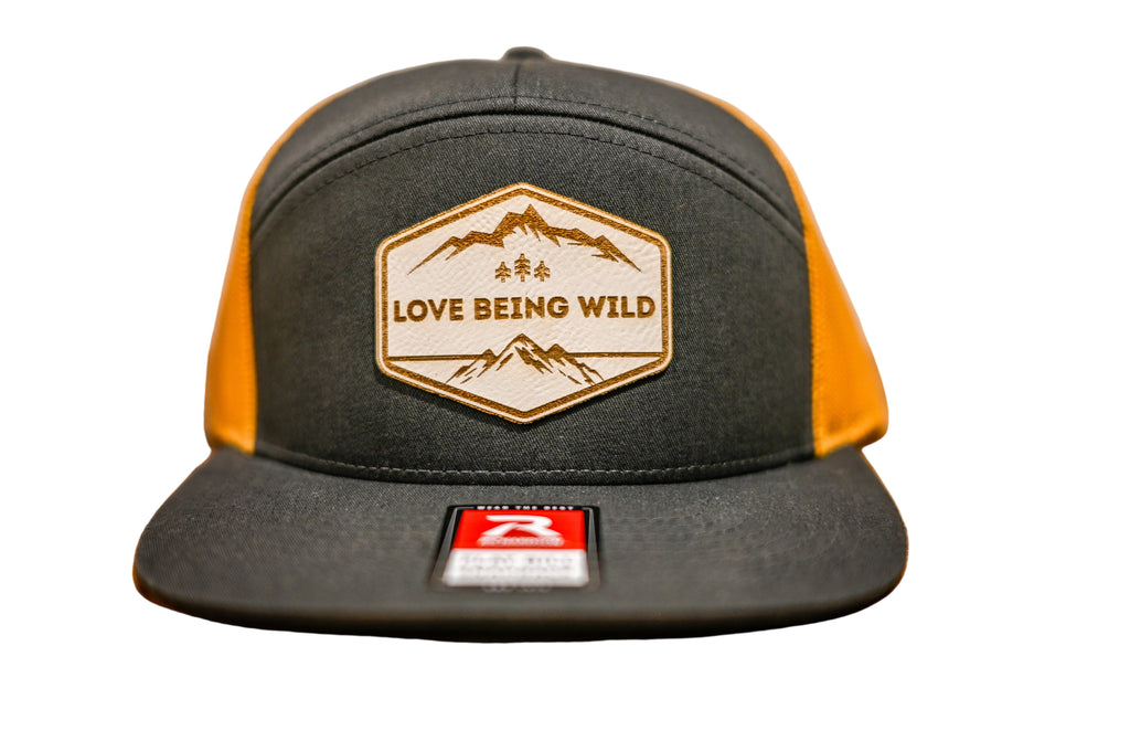 Black and yellow cap with 'Love Being Wild' logo on a leatherette patch