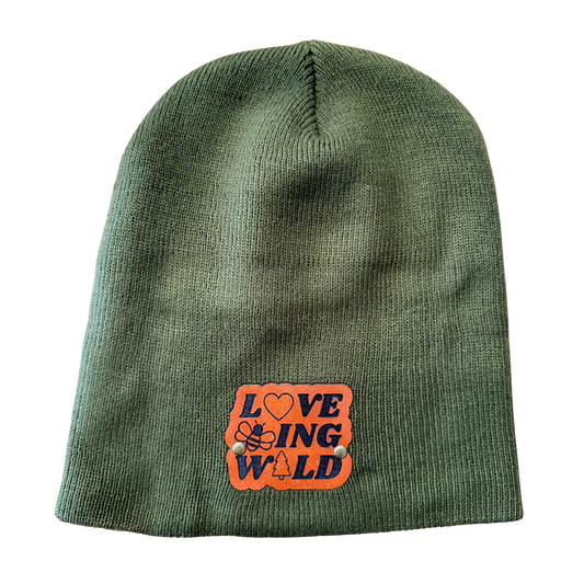 Green beanie with an orange patch featuring text and symbols on a white background