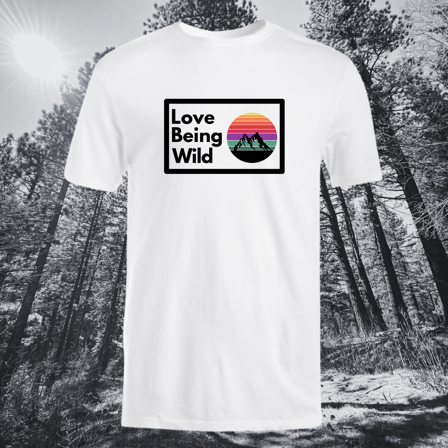 White t-shirt with 'Love Being Wild' graphic in a forest setting