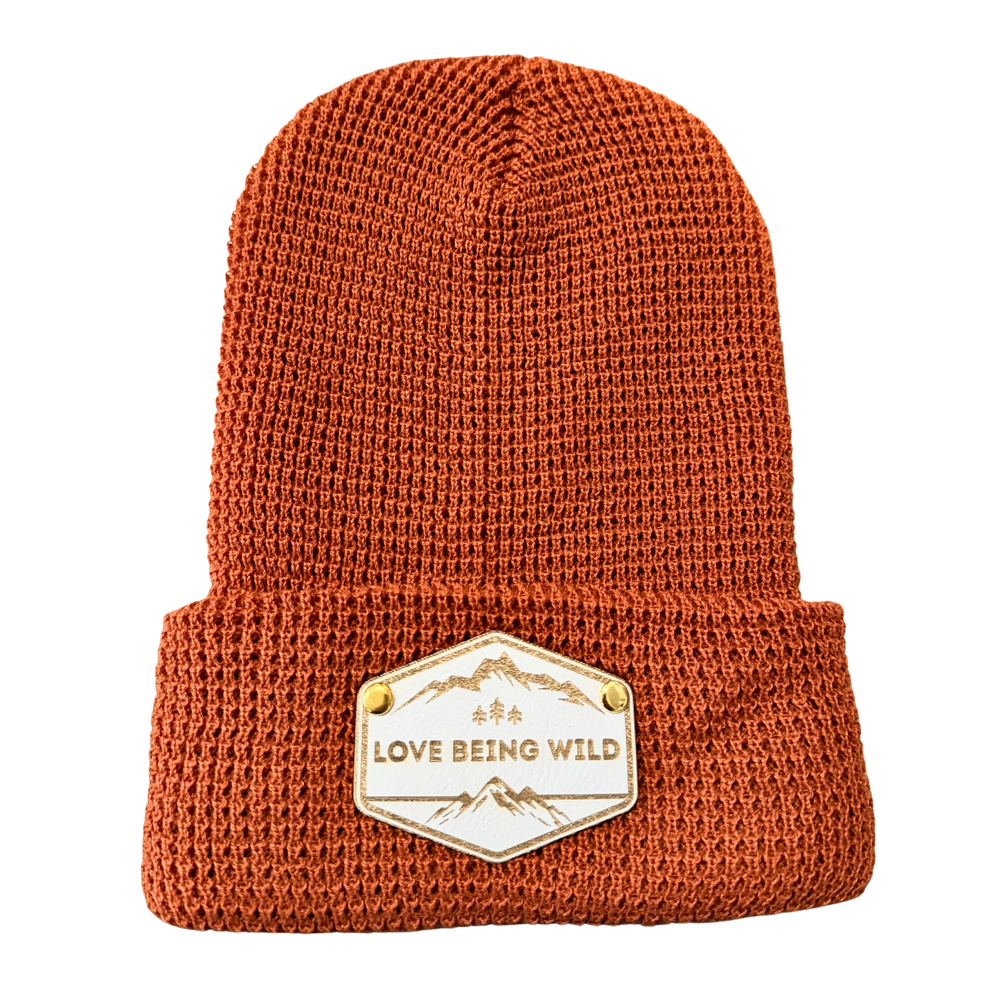 Brown knit beanie with 'Love Being Wild' patch on a white background
