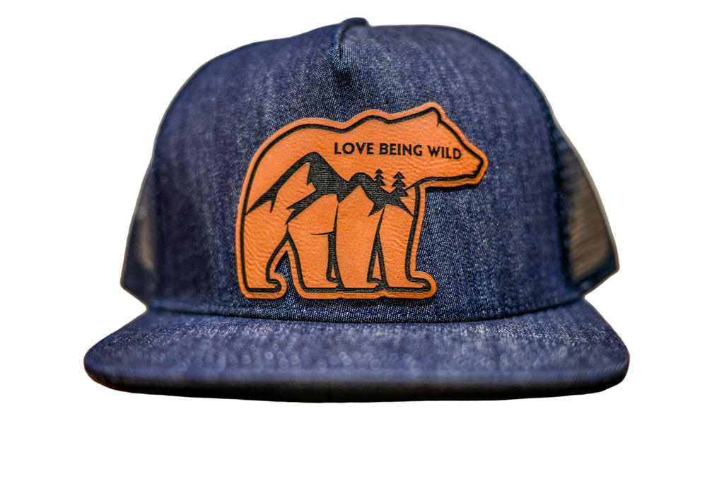 Blue denim cap with bear and mountain design and 'Love Being Wild' text 