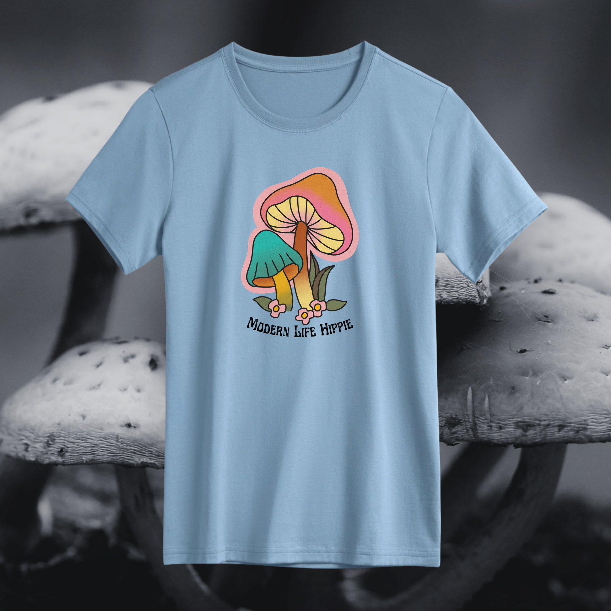 Light blue t-shirt with a colorful mushroom graphic and 'Modern Life Hippie' text on a blurred mushroom background.