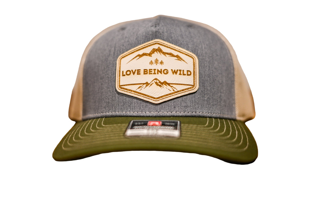 Gray and green cap with 'Love Being Wild' logo on a wooden surface
