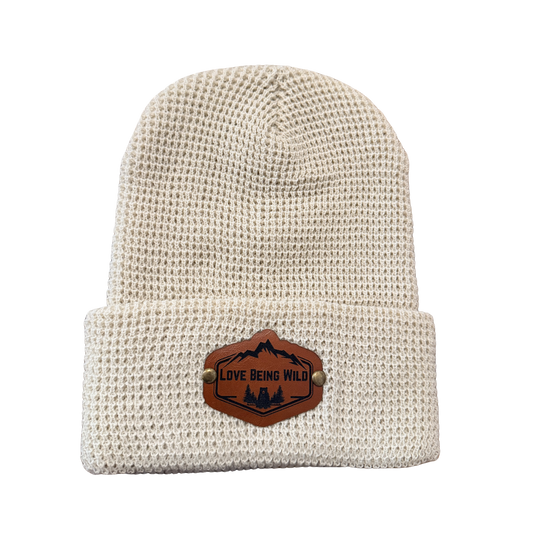 Beige knit beanie with a leather patch on a white background