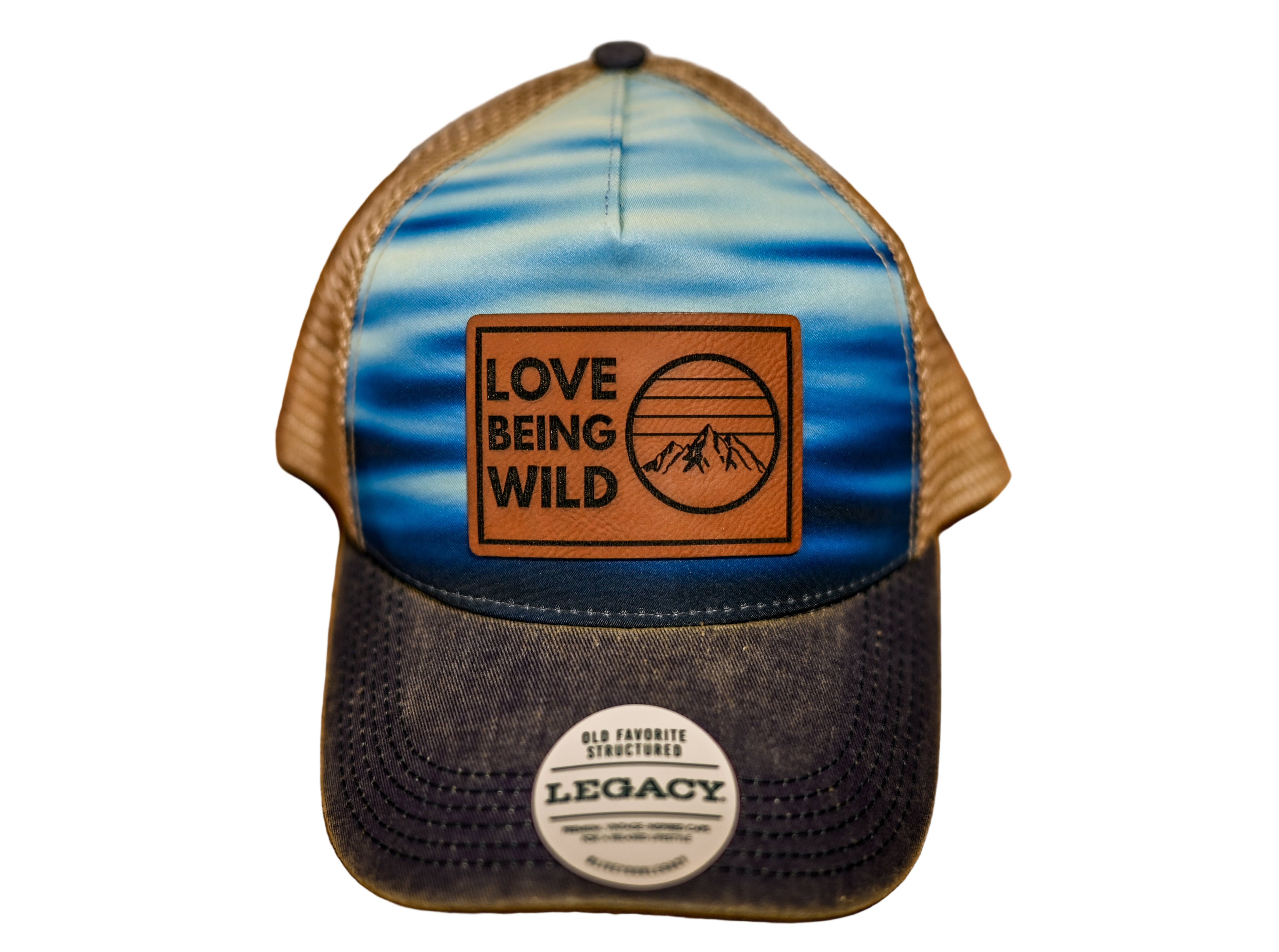 Trucker hat with 'Love Being Wild' logo and 'Legacy' label on a wooden surface